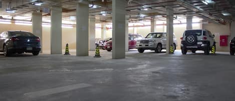 A multi-level parking garage with several cars parked, concrete pillars, and overhead lighting.