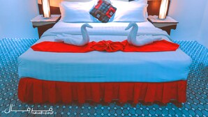 Uma cama com um cobreleito vermelho, dois cisnes brancos e uma almofada decorativa.