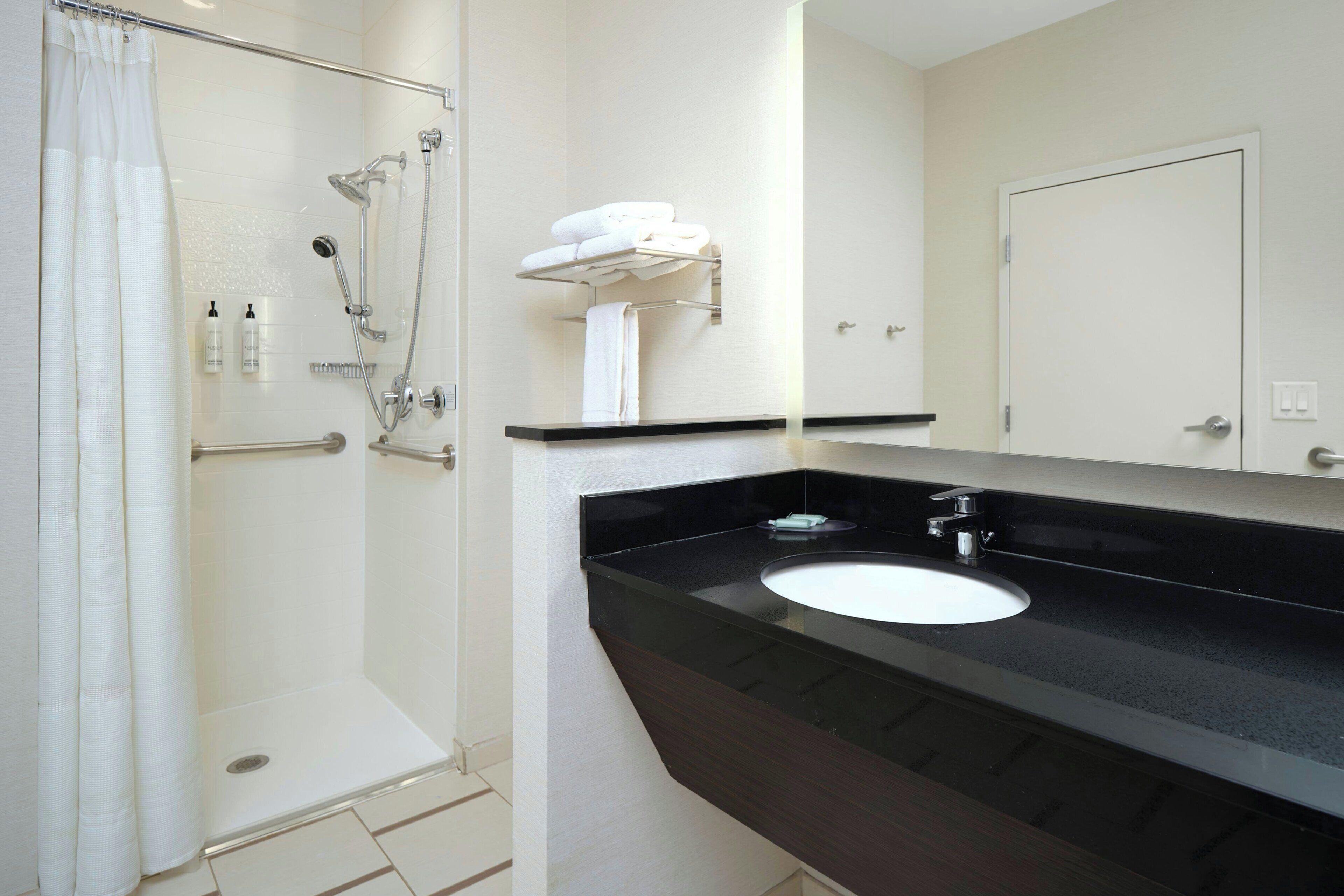 Une salle de bain avec une douche, un lavabo et un miroir.