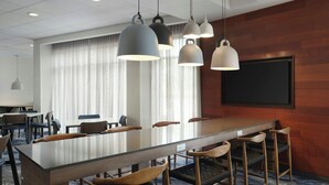 A conference room with a long table, multiple chairs, and pendant lighting. - Fairfield Inn & Suites by Marriott Niagara Falls (Niagara Falls)