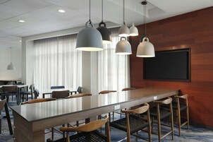 Un salón de conferencias con una larga mesa, varias sillas e iluminación colgante.