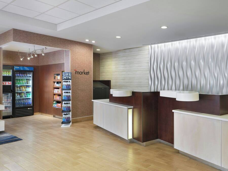 A modern reception area with a counter, a refrigerator stocked with beverages, and a life fountain.