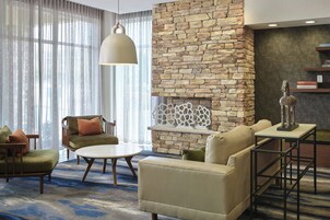 Una sala de estar moderna con chimenea de piedra, asientos cómodos y un ventanal con cortinas translúcidas.