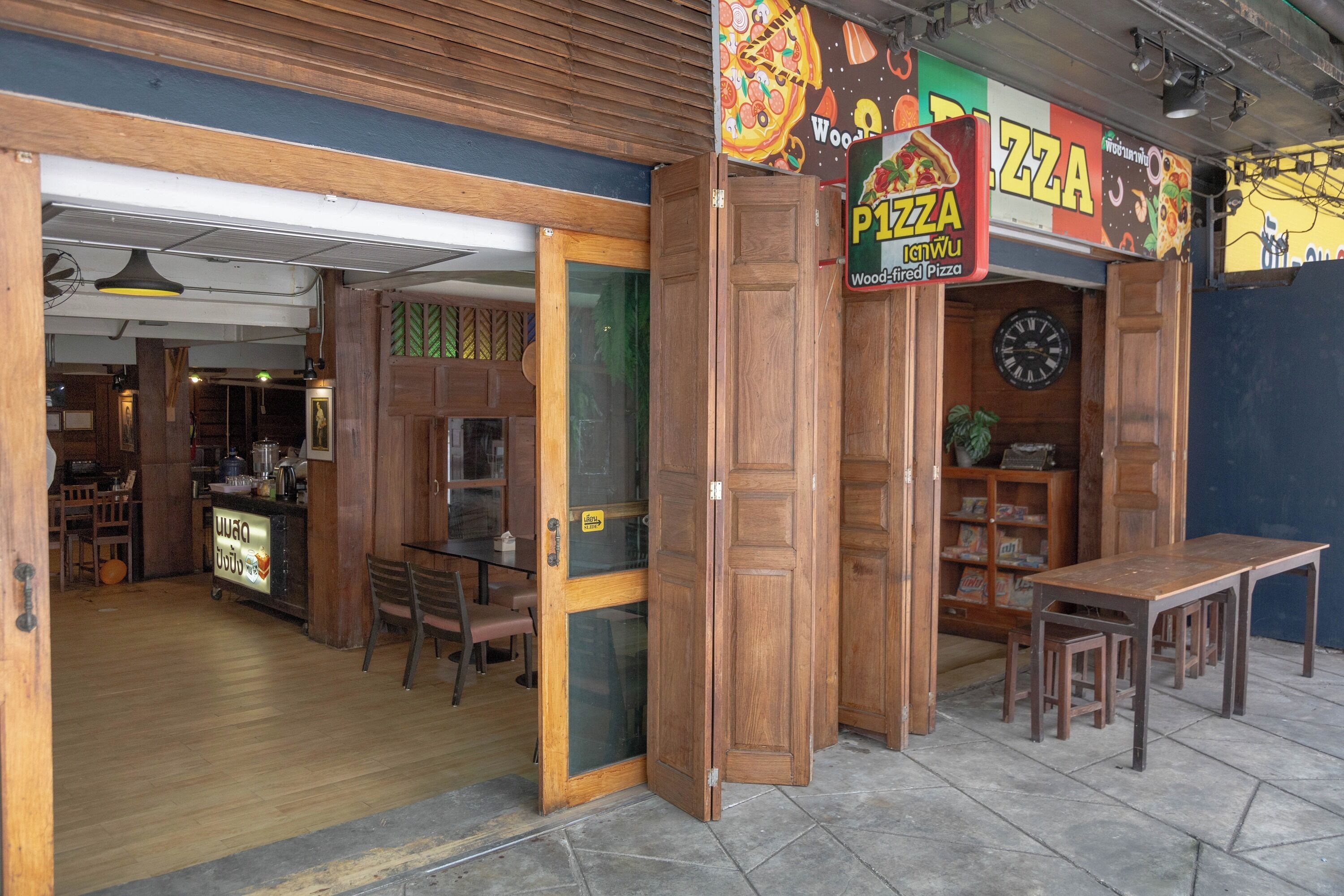 A restaurant with a wooden interior, a pizza sign, and a counter with a menu.