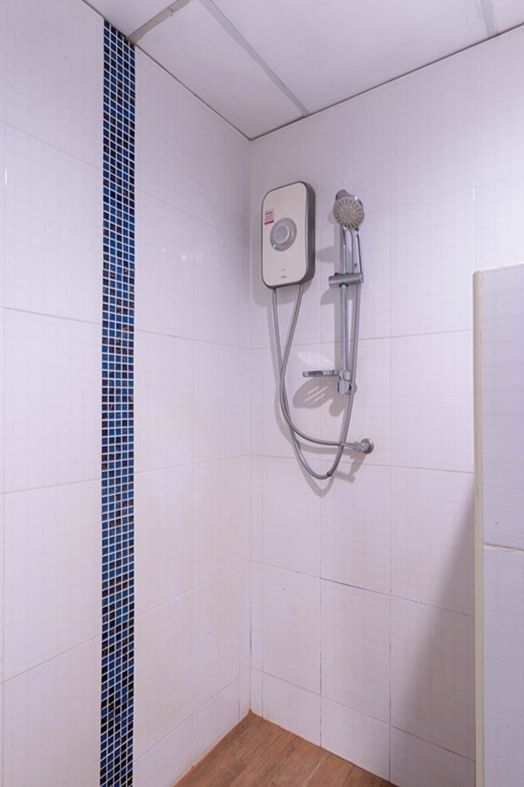 A shower with a control panel and handheld showerhead mounted on a white tiled wall.