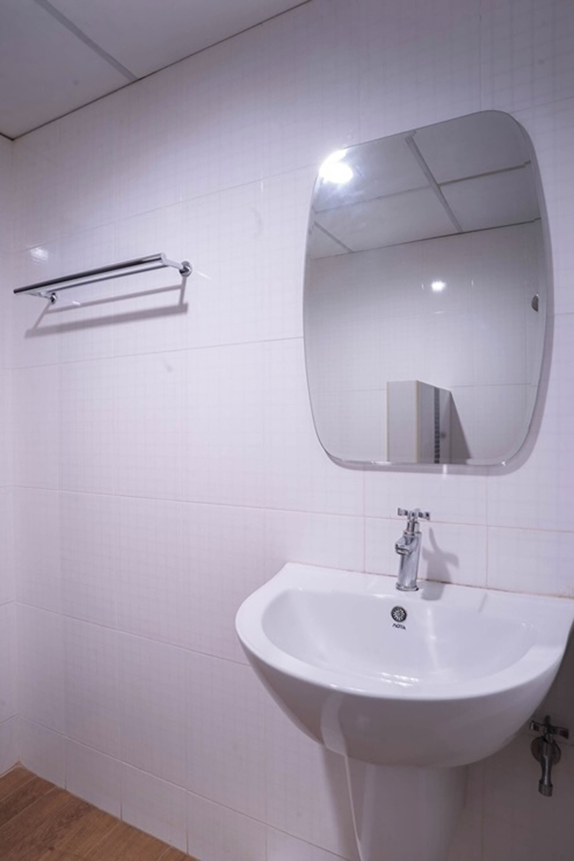 A bathroom with a white sink, a mirror, and a towel rack.