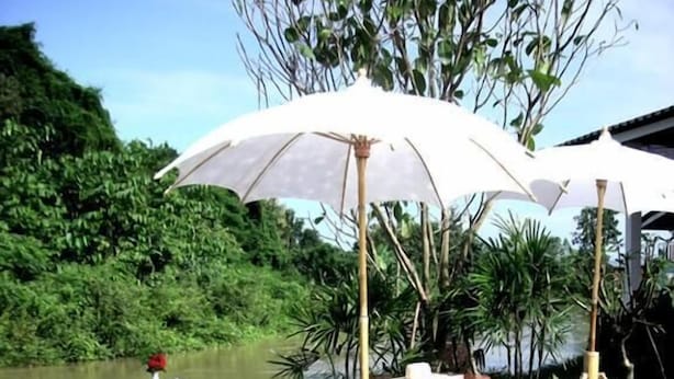 A wooden deck with a pool, surrounded by greenery and a white umbrella. - Baan Rim Klong Resort (Sukhothai)