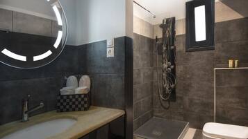 A modern bathroom with a round mirror, a sink, a shower, and a toilet.