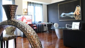 A modern living room with a large vase, a flat-screen TV, a painting, and a dining area. - Andromeda Suites and Apartments (Athens)
