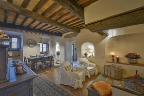 A cozy dining area with a wooden ceiling, a dining table with chairs, and a kitchen in the background. - Villa Casalguidi (Serravalle Pistoiese)