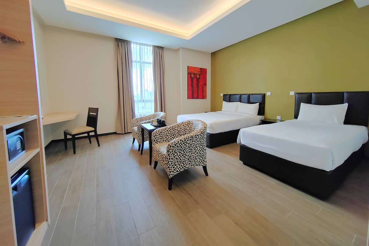 A hotel room with two beds, a sofa, a dining table, and a TV.