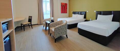 Habitación de hotel con dos camas, un sofá, una mesa de comedor y un televisor.