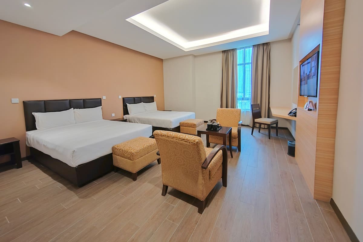 A hotel room with two beds, a sofa, a desk, and a TV.