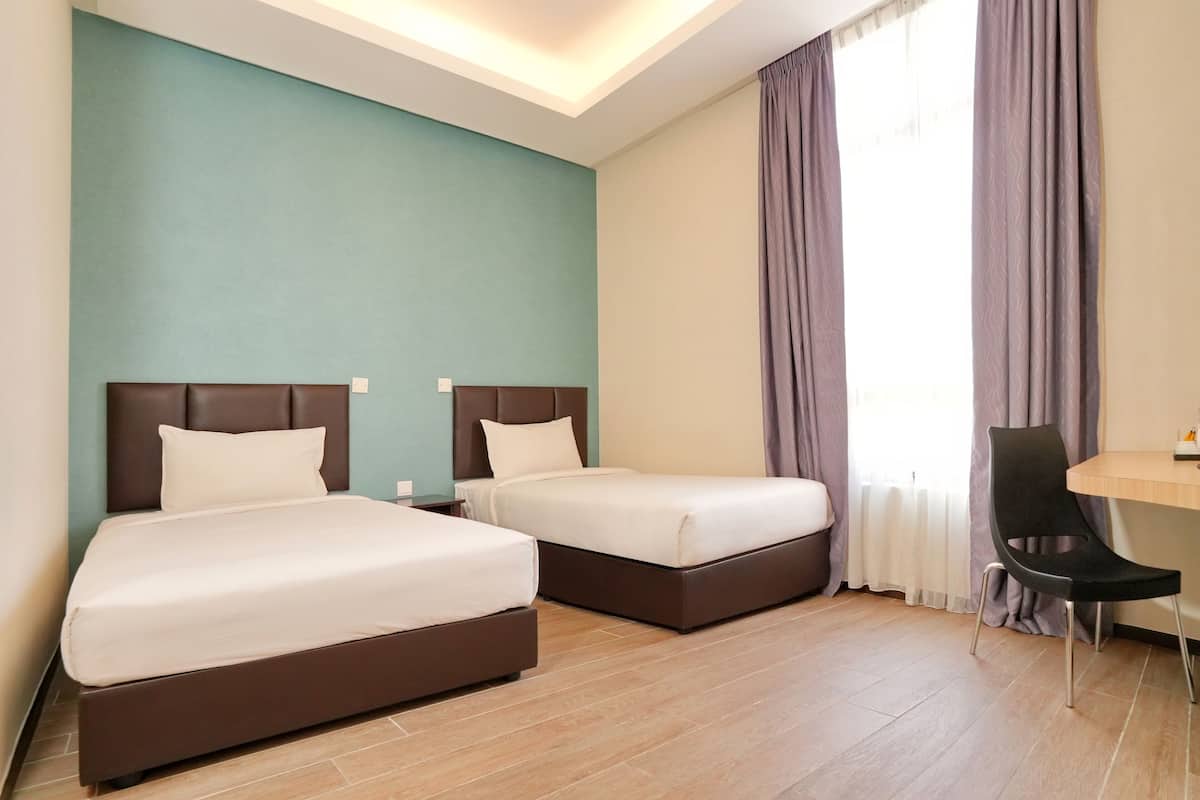 A hotel room with two beds, a desk, and a chair.