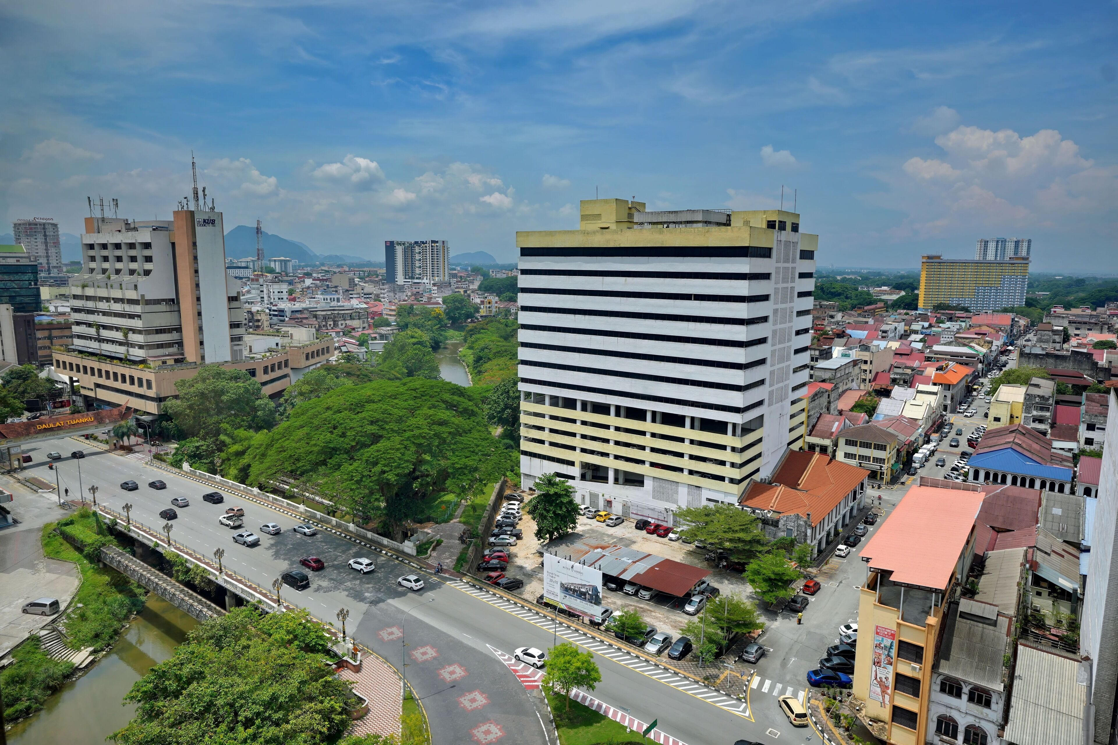 A cityscape with a prominent multi-story building, a bridge, and a river.