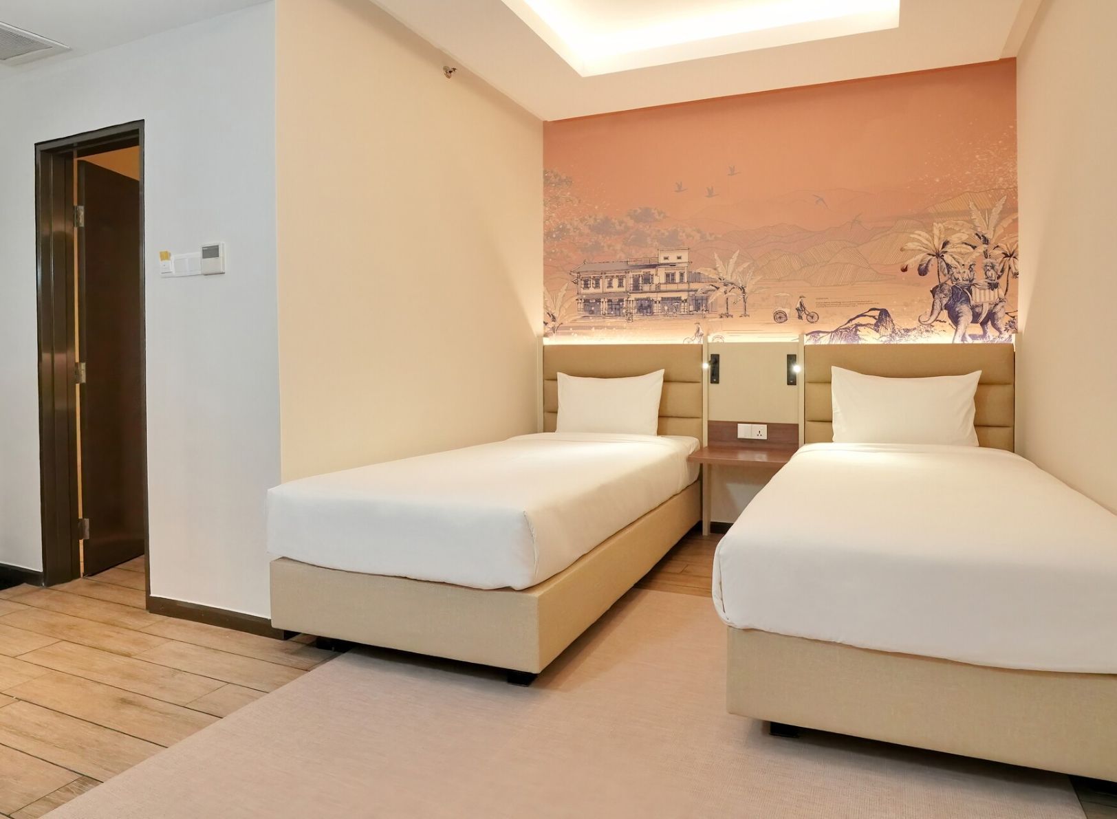 A hotel room with two beds, a wooden floor, a door, and a mural on the wall.
