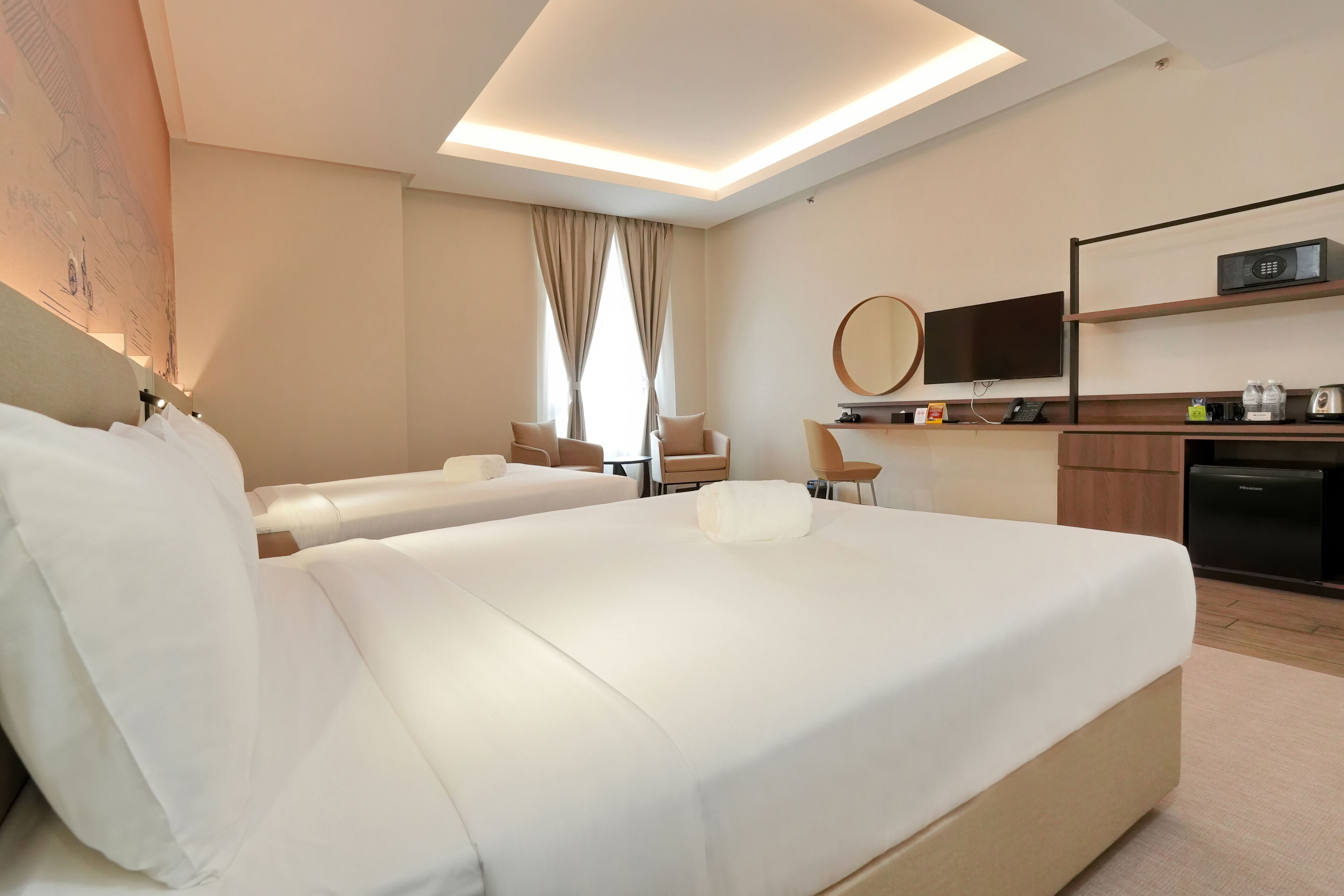 Una habitació d'hotel amb dos llits, un escriptori, una televisió i un microones.