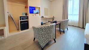 Habitación de hotel con sofá, televisión, escritorio y minibar.
