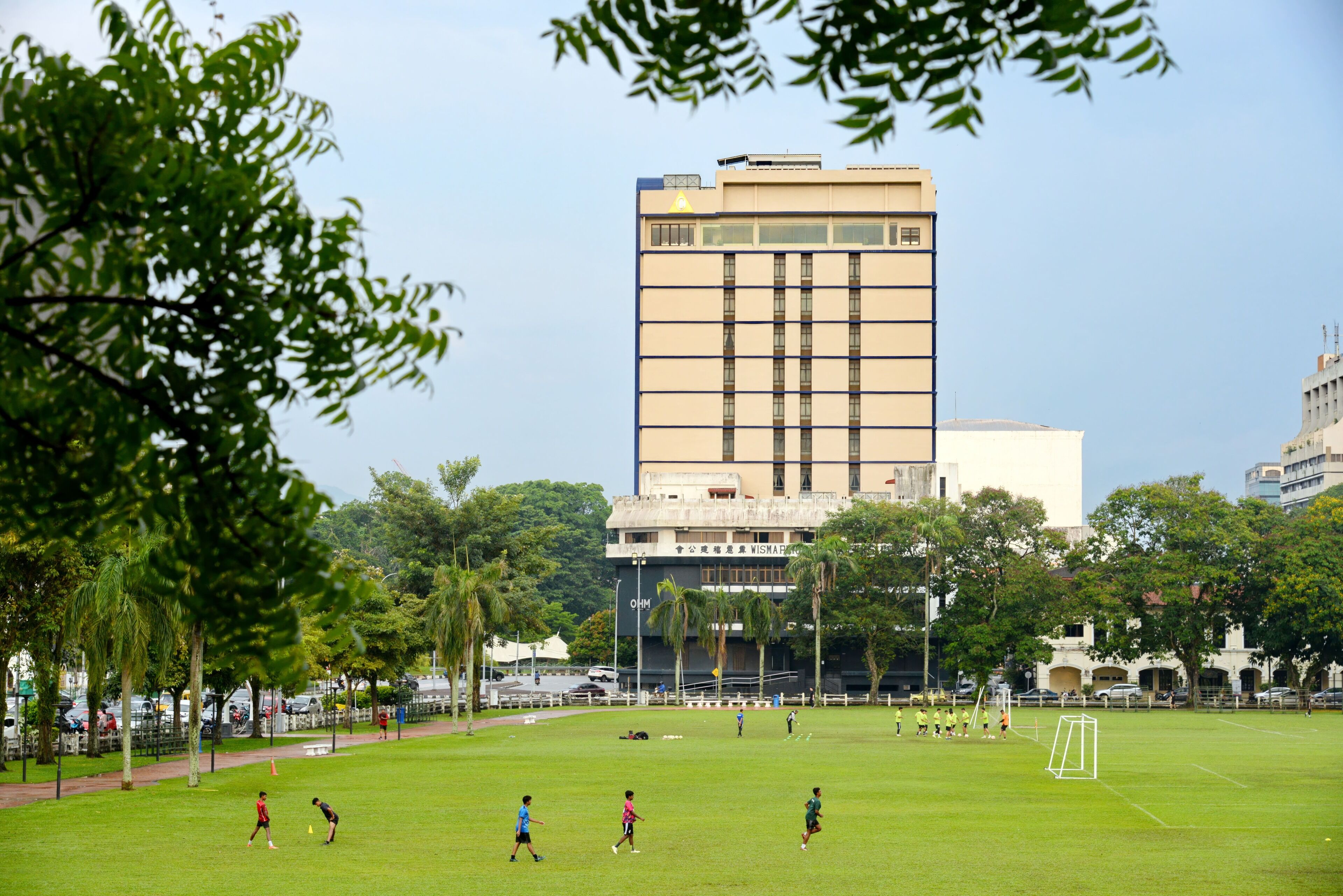 A soccer field with players, surrounded by trees and buildings.
