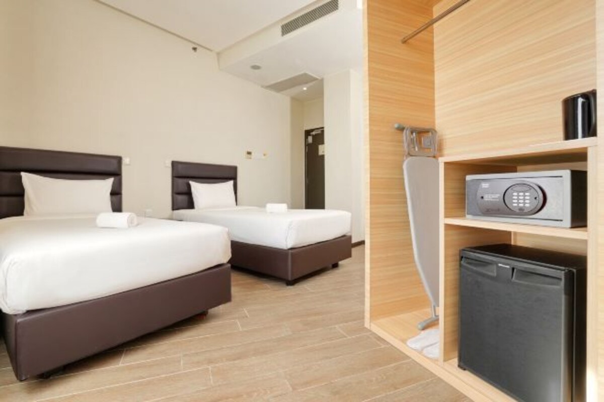Habitación de hotel con dos camas, microondas y un refrigerador pequeño.