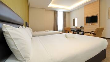 A hotel room with two beds, a desk, a chair, a TV, and a bathroom.