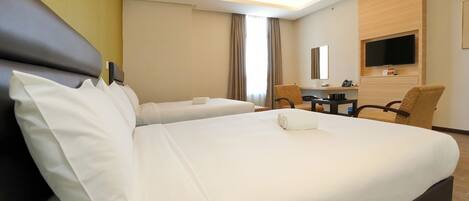 A hotel room with two beds, a desk, a chair, a TV, and a bathroom.
