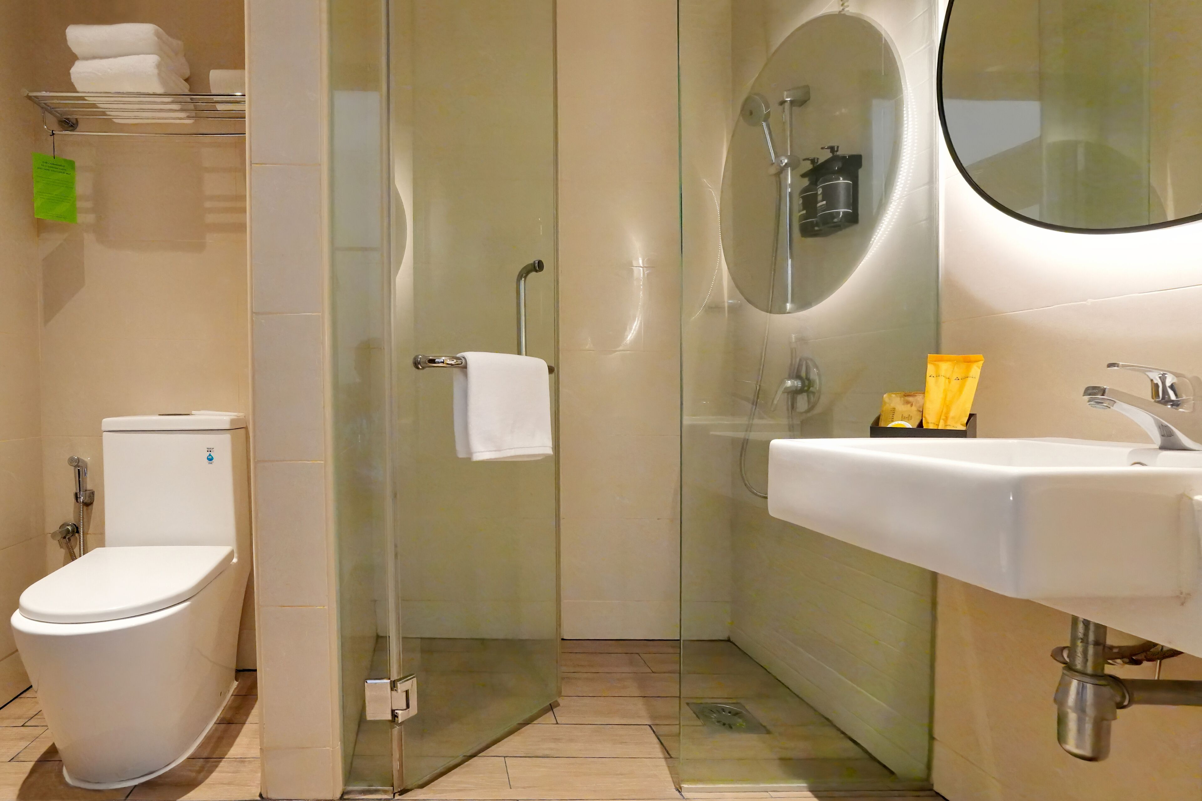 A modern bathroom with a toilet, glass shower enclosure, and a sink with toiletries.