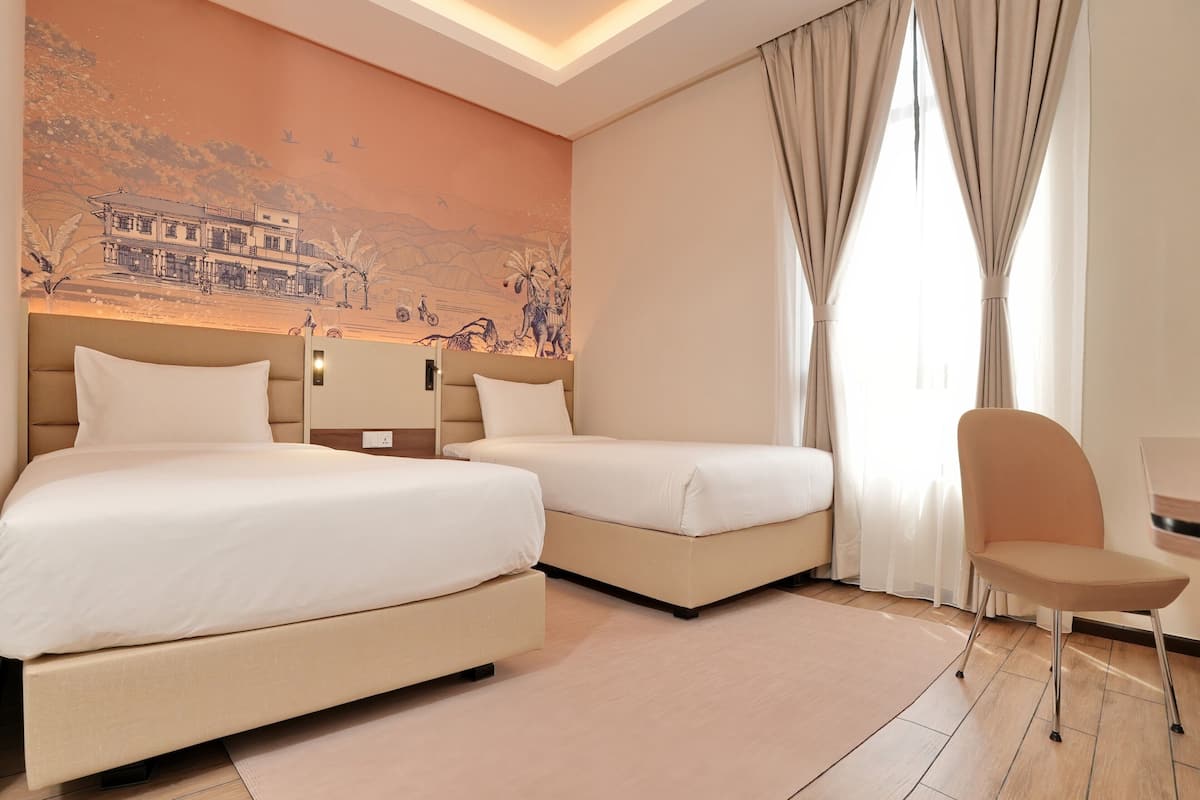 A hotel room with two beds, a chair, a desk, and a mural on the wall.