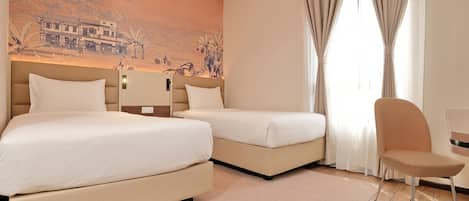 A hotel room with two beds, a chair, a desk, and a mural on the wall.