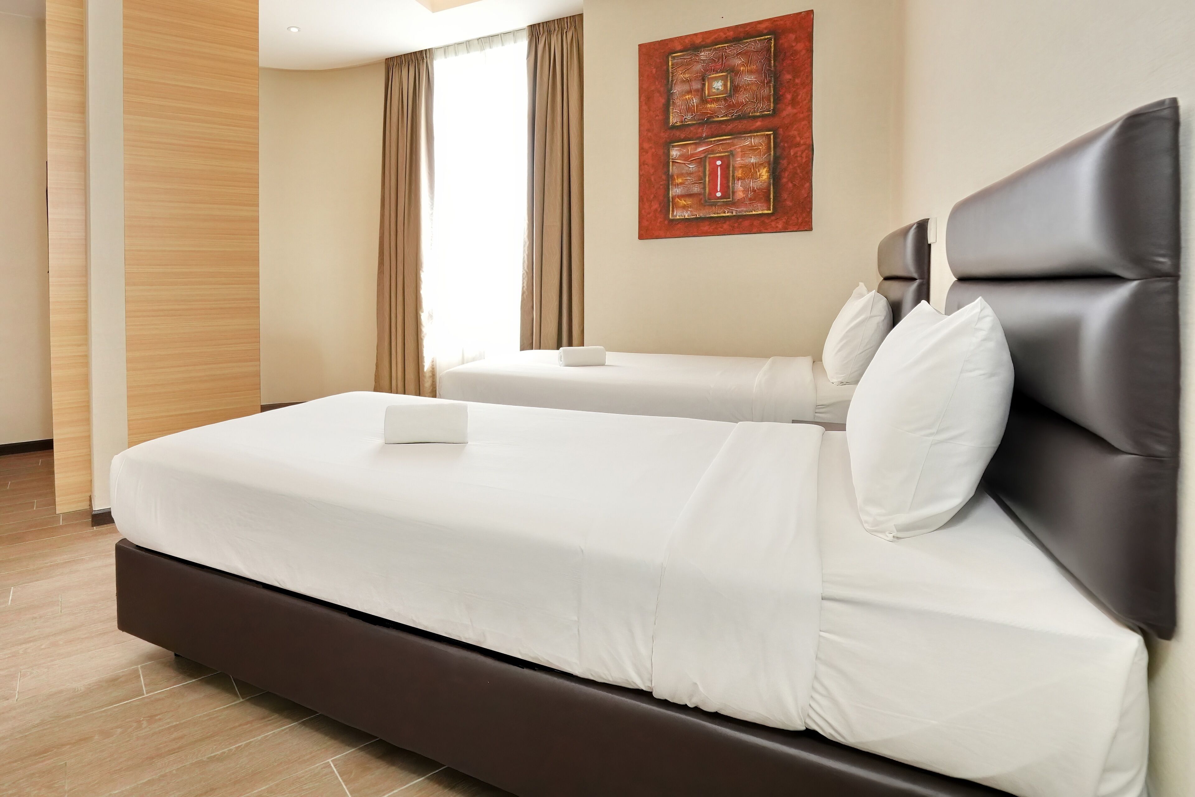 Una habitación de hotel moderna con una cama grande, una cama más pequeña y un elemento decorativo en la pared.