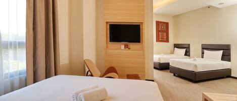 A hotel room with a large bed, two smaller beds, a TV mounted on the wall, and a wooden panel design.