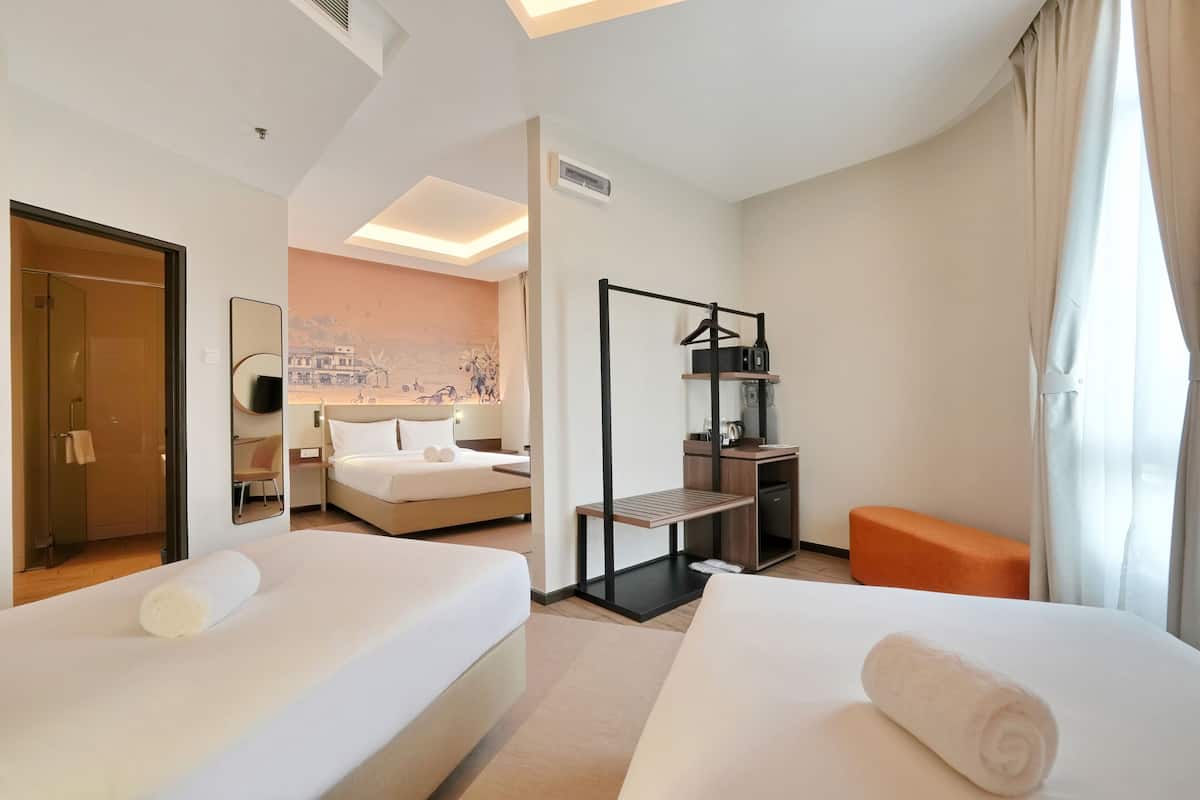 A hotel room with two beds, a desk, a chair, a small table, and a sofa.