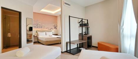 A hotel room with two beds, a desk, a chair, a small table, and a sofa.