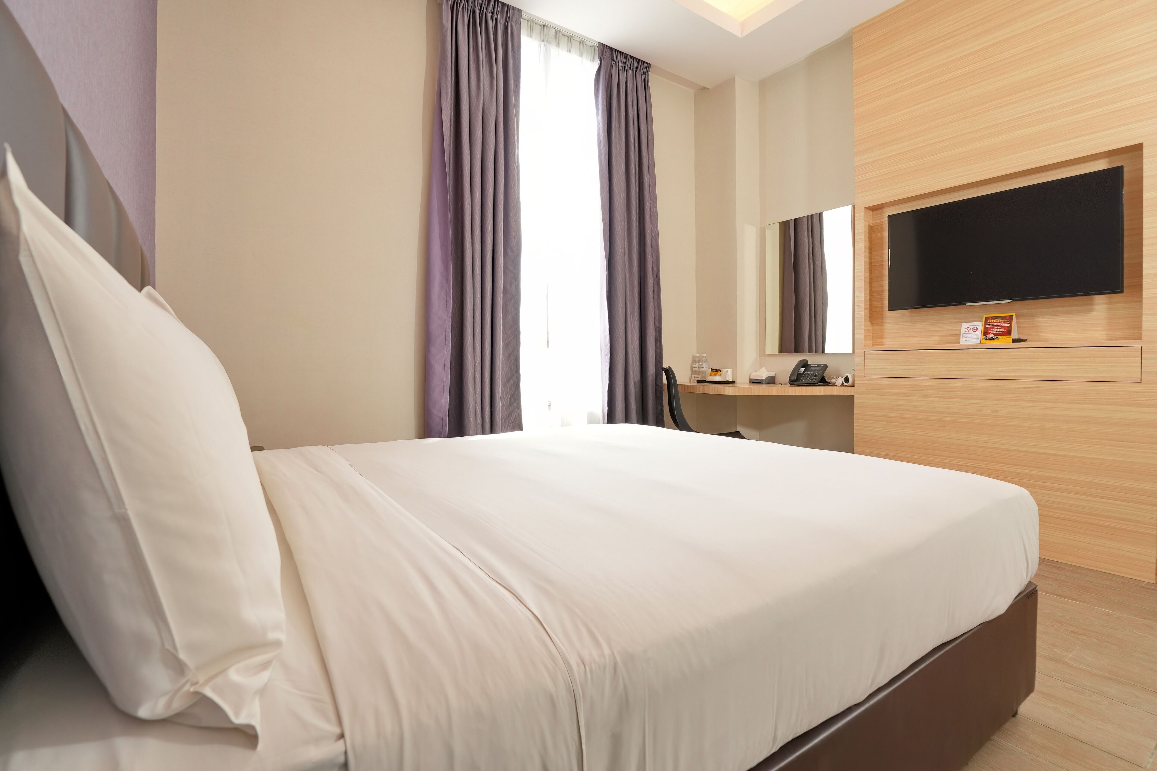 Habitación de hotel con una cama grande, un televisor de pantalla plana montado en la pared y un diseño de paneles de madera en la pared.