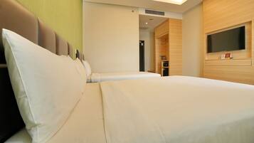 Une chambre d’hôtel avec un grand lit, un téléviseur à écran plat fixé au mur et une armoire en bois.