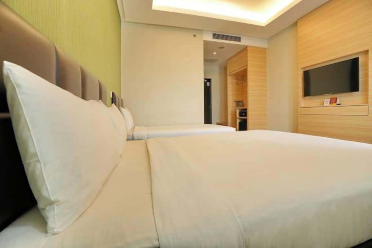 Una habitación de hotel con una cama grande, un televisor de pantalla plana en la pared y un armario de madera.