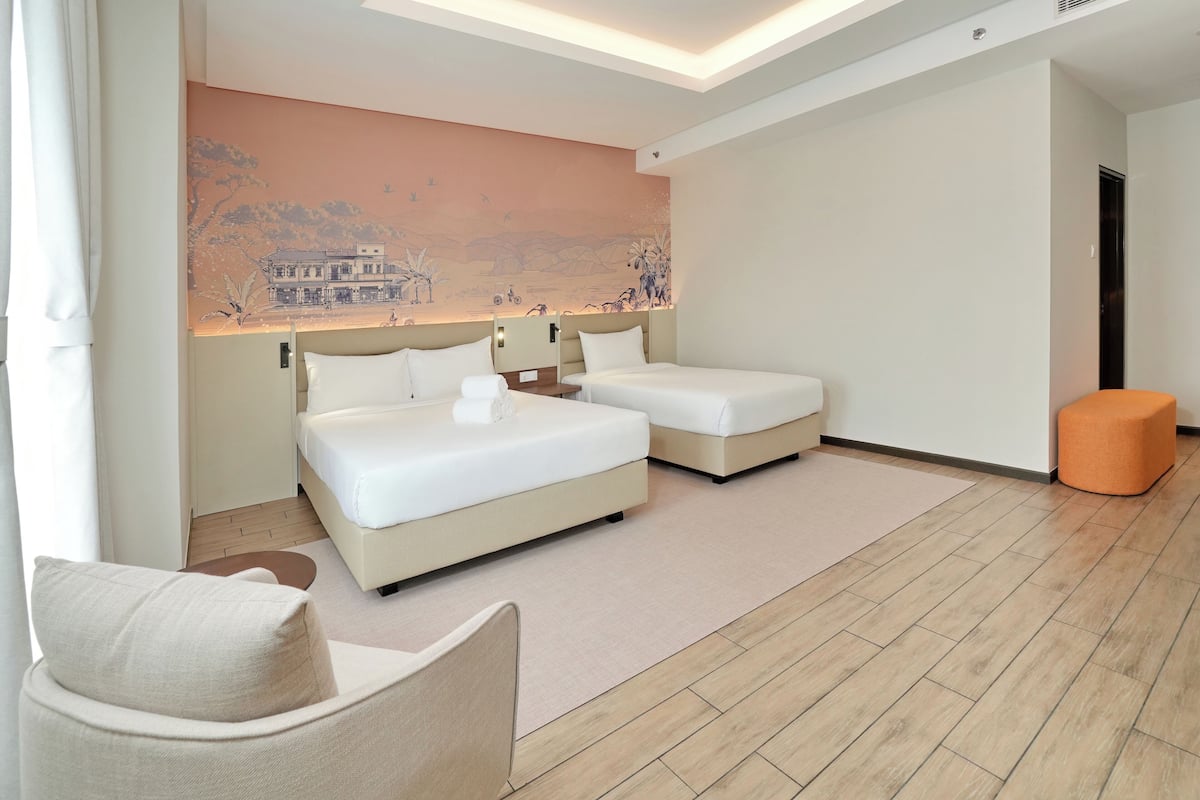A modern hotel room with two beds, a seating area, and a mural on the wall.