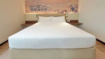A neatly made bed with a white sheet and a beige mattress in a hotel room.
