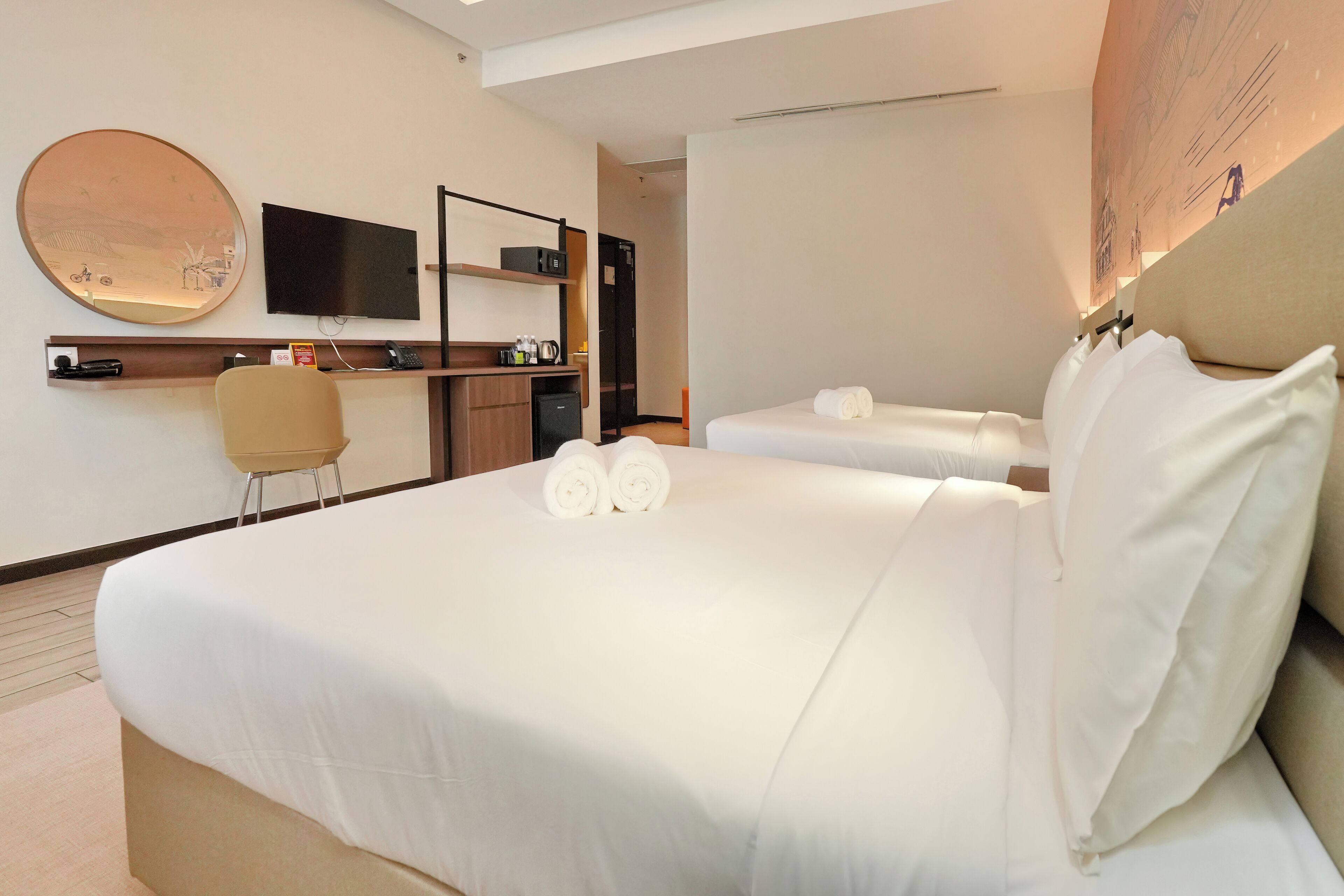 A hotel room with a large bed, a desk with a chair, a flat-screen TV, and a large mirror.