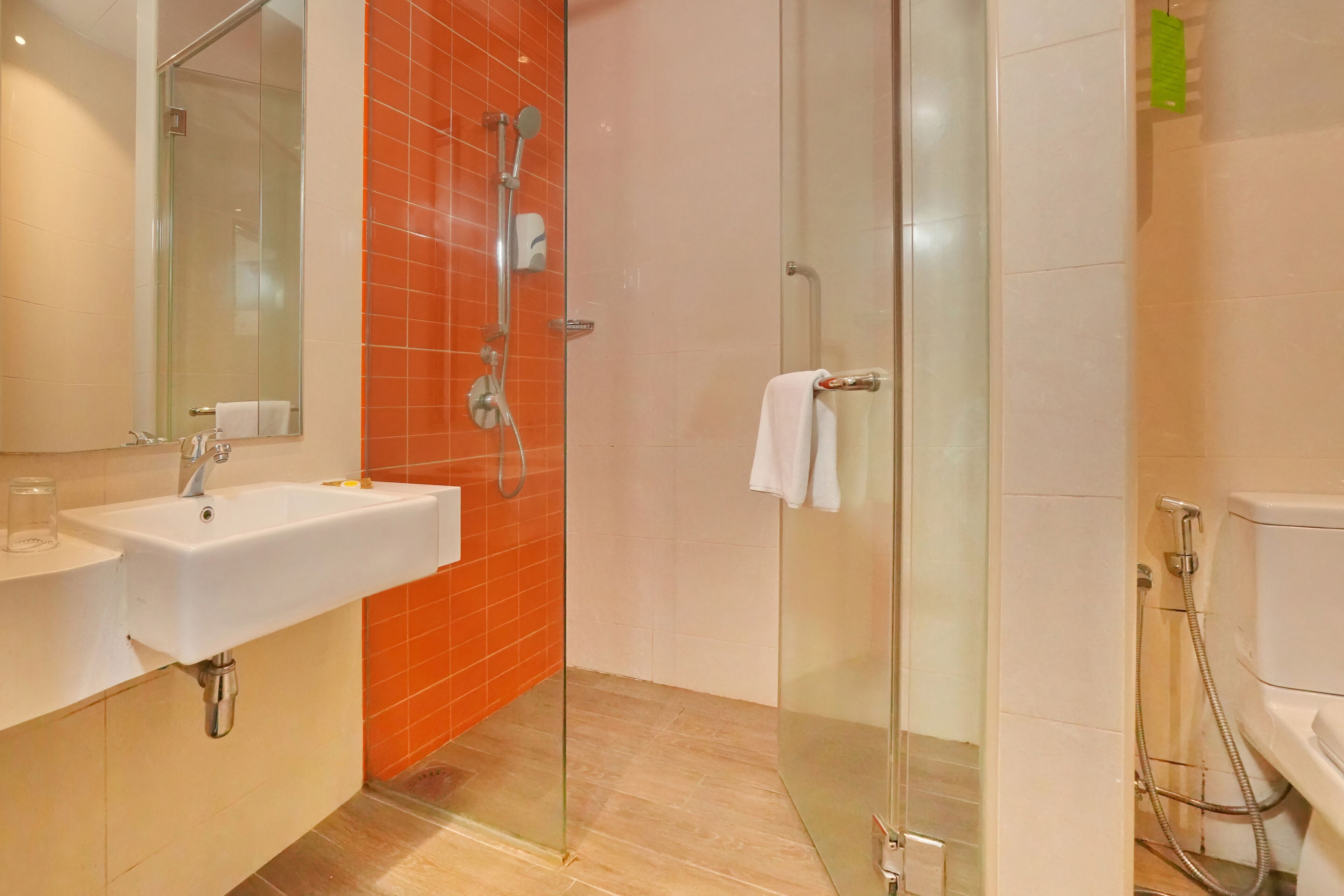 A modern bathroom with a glass-enclosed shower, a white sink, and a toilet.