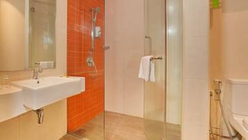 A modern bathroom with a glass-enclosed shower, a white sink, and a toilet.