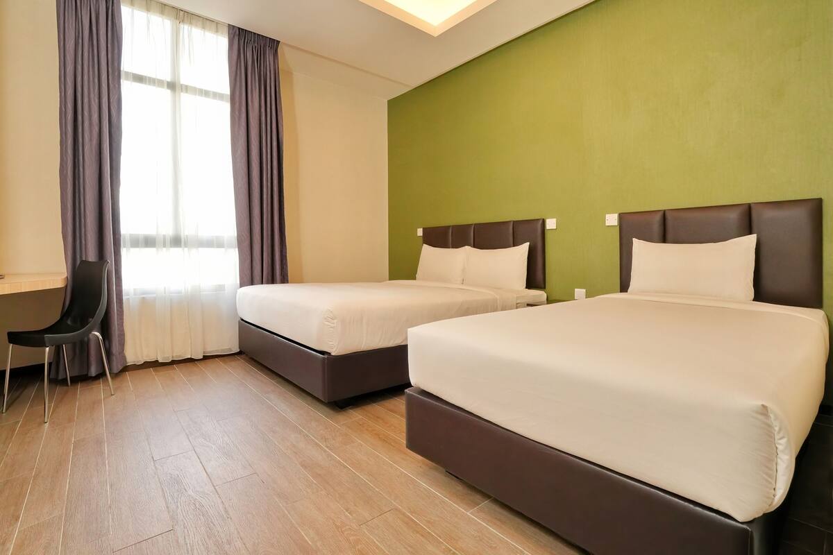 A hotel room with two beds, a desk, and a chair.