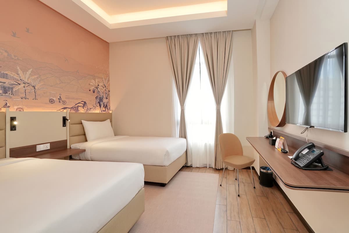 A hotel room with two beds, a desk with a telephone, a chair, and a large mirror.