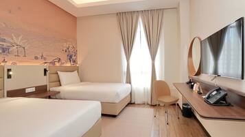 A hotel room with two beds, a desk with a telephone, a chair, and a large mirror.