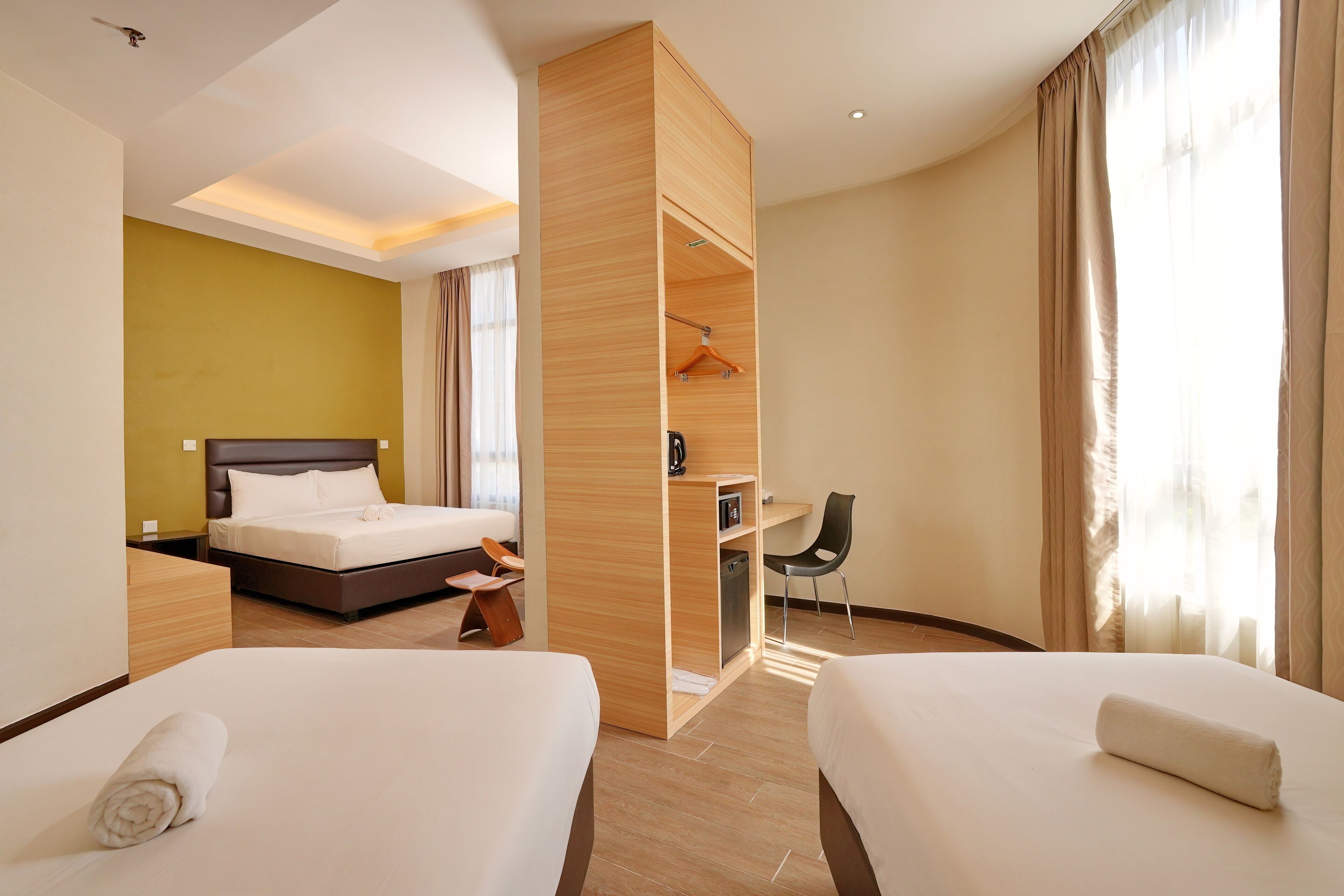Ein Hotelzimmer mit zwei Betten, einem Schreibtisch und einem Kleiderschrank.