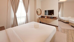 Habitación de hotel con una cama grande, un escritorio con televisor de pantalla plana, una silla y un sofá.