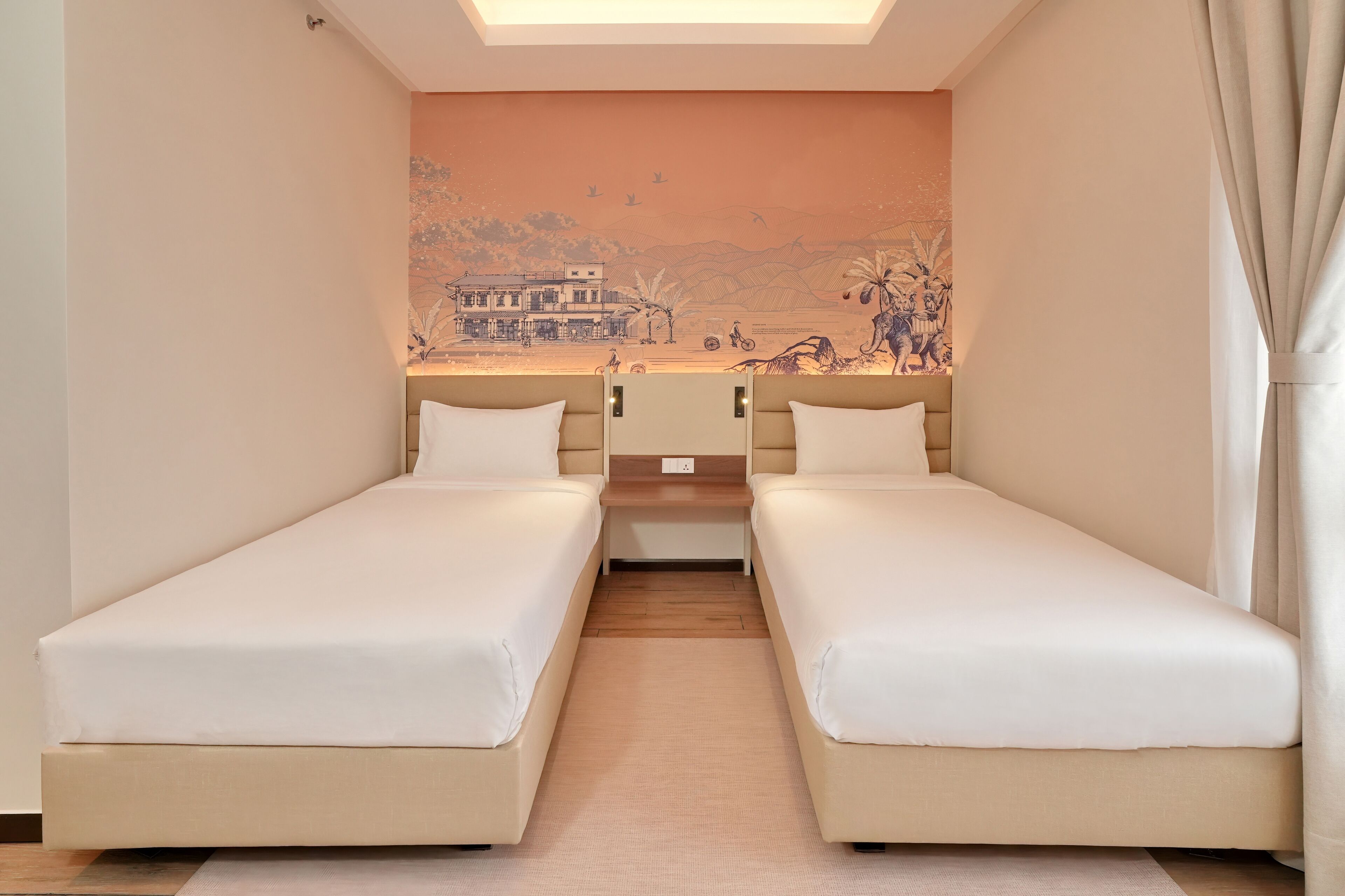 Een kamer met twee eenpersoonsbedden, een kleine tafel en een muurschildering.
