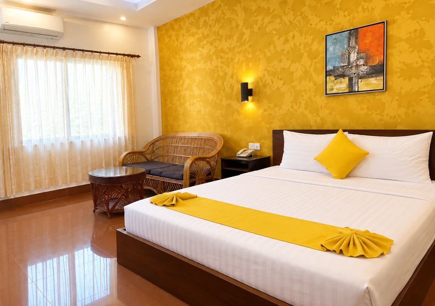 Habitación de hotel con cama, una silla, una mesita y un cuadro en la pared.