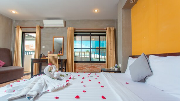 Habitación de hotel con cama, escritorio, silla y ventana con vista al exterior.