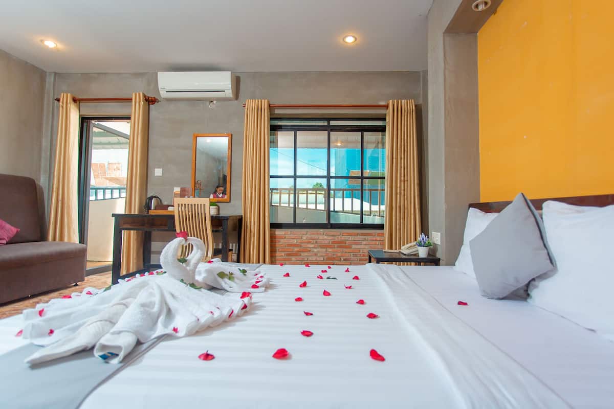 A hotel room with a bed, a desk, a chair, and a window with a view of the outside.